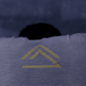 A person wearing a Group Evolution shirt is leaning forward with their hands on the wall, stretching. The back of the shirt features a Group Evolution logo.