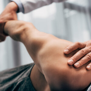 A physical therapist manipulates a patient’s arm and shoulder while the patient lies on a treatment table, focusing on rehabilitation or injury recovery.