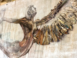 Mixed-media artwork of a figure with outstretched arms, featuring a painted body and textured wings made from layered materials resembling feathers, evokes the elegance of a glorious chateau in the Loire, set against a faded, neutral background.