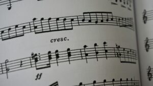 Close-up of a sheet of music with musical notes, a cresc. marking for crescendo, and dynamic notation ff on a white background. The image focuses on the printed staves and symbols.