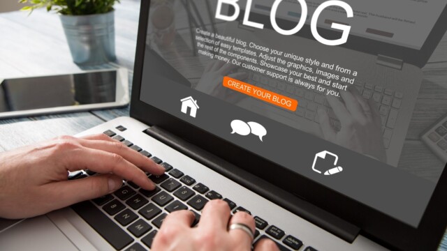 A person types on a laptop showing the Blog webpage. The screen prominently displays BLOG, with CREATE YOUR BLOG highlighted. Text and icons related to blogging are visible against an indoor backdrop with a plant.