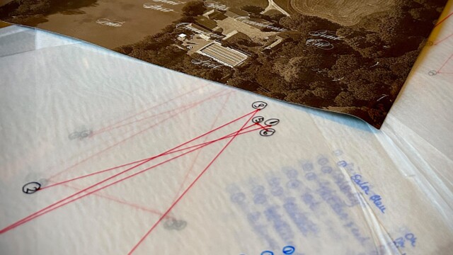 A photo of clues at our immersive murder mystery - a map of the Chateau Estate and pages marked with red lines and handwritten blue notes, detailing key locations and connections.