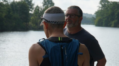 A man standing next to a man wearing a backpack.